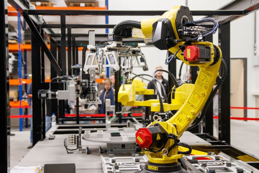 pexels-photo-34207359-1 Close-up of a yellow industrial robotic arm in action at a modern manufacturing facility.